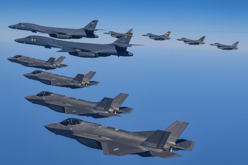 In this photo provided by South Korea Defense Ministry, U.S. Air Force B-1B bombers, top center, fly in formation with South Korea's Air Force F-35A fighter jets and U.S. Air Force F-16 fighter jets, top right, over the South Korea Peninsula during a joint air drill in South Korea, Sunday, March 19, 2023.