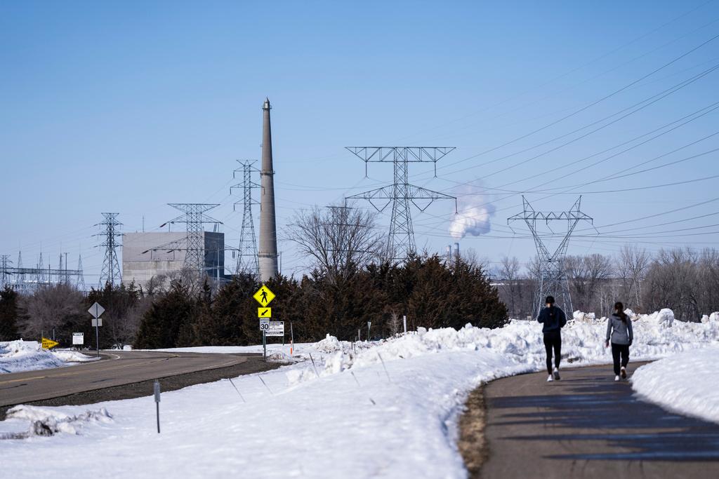 People walk on a trail at the Montissippi County Park near the Xcel Energy Monticello Generating Plant, a nuclear power plant, in Monticello, Minn., on Friday, March 24, 2023.