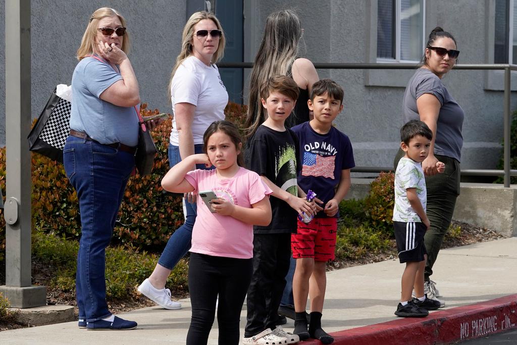 People gather across the street from local fitness center and library where a lockdown occurred in response to a shooting in Roseville, Calif., Thursday, April 6, 2023. Roseville Police say at least three people have been hospitalized.