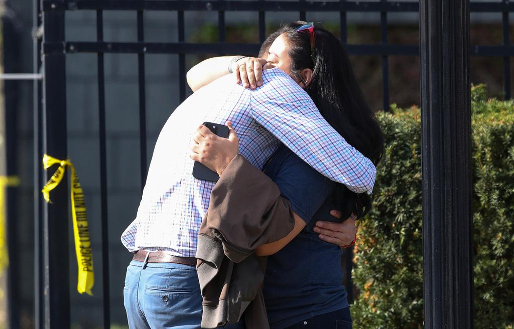 Two people embrace outside of a building where a shooting took place in Louisville, Ky.