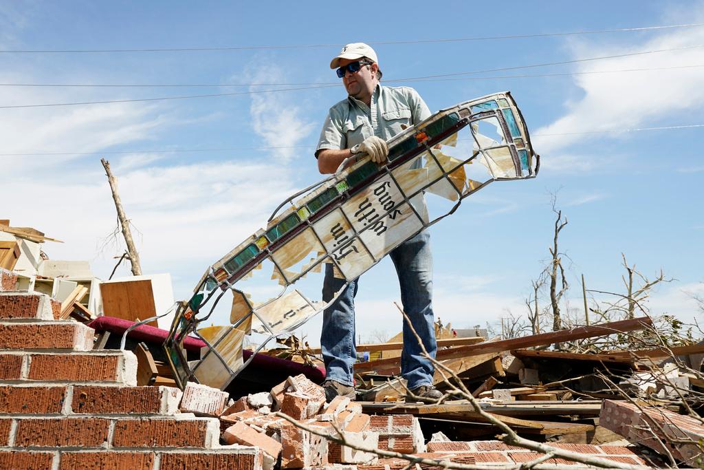 Charlie Weissinger carefully removes a stained glass window frame as he searches for his family's stained glass window in the rubble left from a March 24 tornado, that hit The Chapel of The Cross Episcopal Church in Rolling Fork, Miss.
