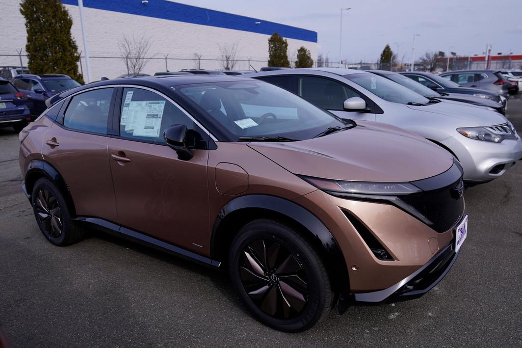 A Nissan ARIYA electric vehicle is parked on a car dealer's lot.