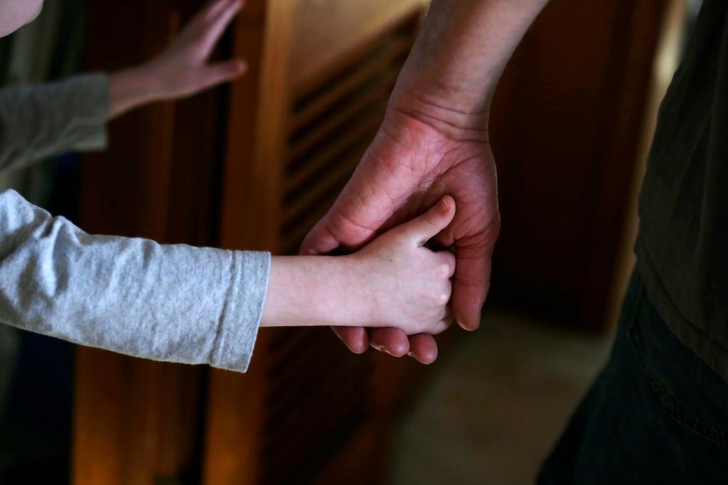 Boy with autism holds the hand of his adoptive father as they prepare to leave for a family outing from their home in Springfield, Mass.