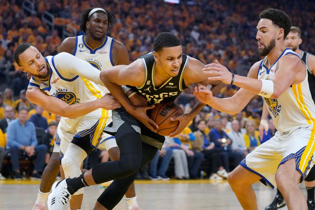 Sacramento Kings forward Keegan Murray, middle, holds onto the ball between Golden State Warriors guard Stephen Curry, left, and guard Klay Thompson during the first half of Game 4 in the first round of the NBA basketball playoffs in San Francisco, Sunday, April 23, 2023. 
