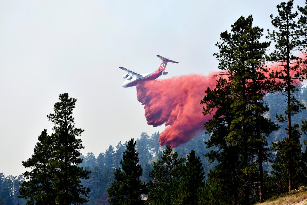 An aircraft drops fire retardant to slow the spread of a fire