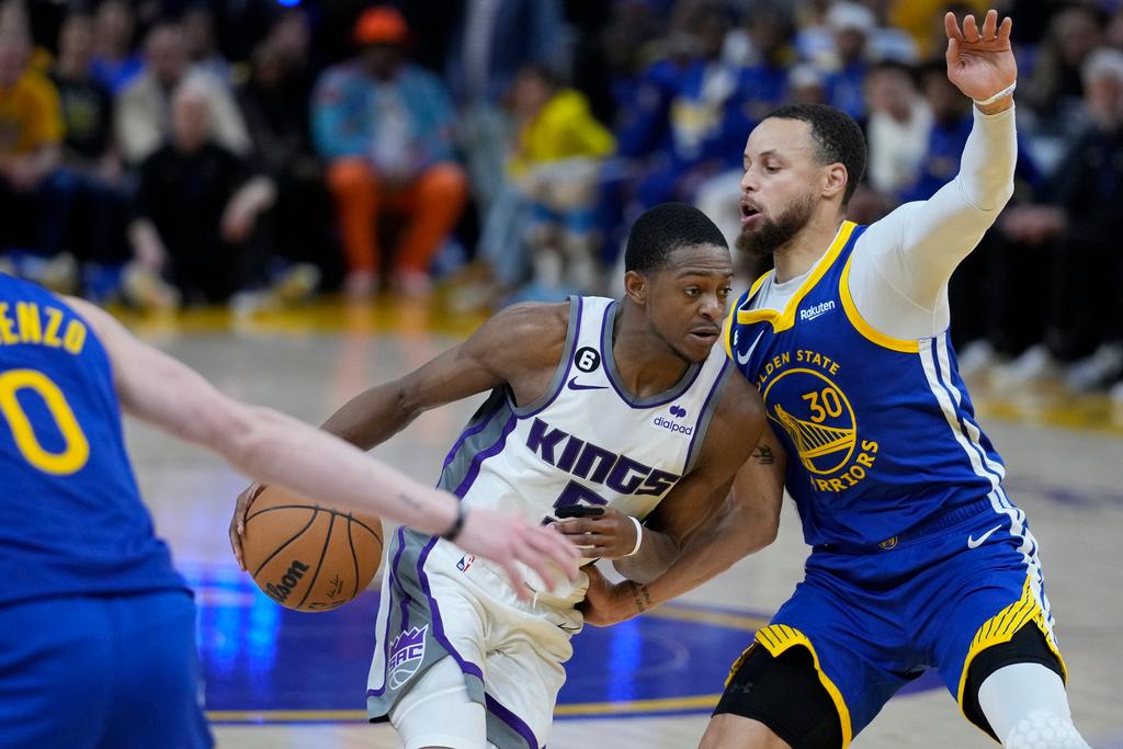 Sacramento Kings guard De'Aaron Fox, center, tries to get past Golden State Warriors guard Stephen Curry, right, during the first half of Game 6 of a first-round NBA basketball playoff series in San Francisco, Friday, April 28, 2023.
