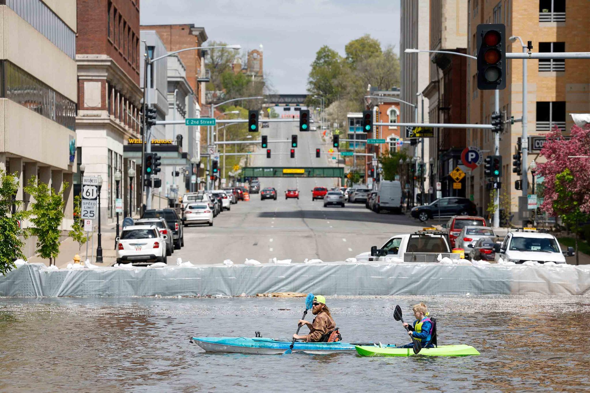 A group of kayakers paddle along River Drive along the HESCO sand barriers protecting downtown from the rising Mississippi River, Saturday, April 29, 2023, in Davenport, Iowa.