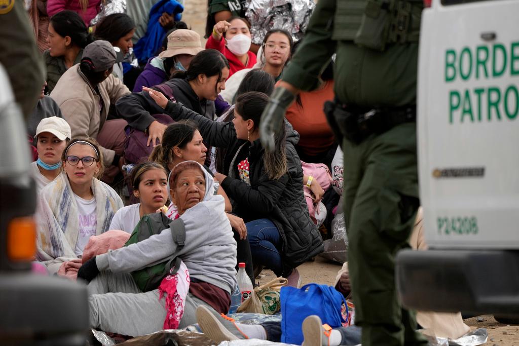 People wait to apply for asylum between two border walls in San Diego.