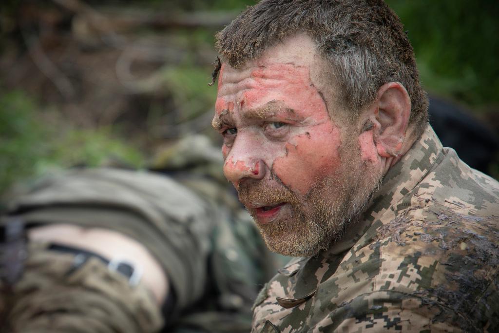Ukrainian soldier as military medics give first aid to wounded soldiers on the road near Bakhmut