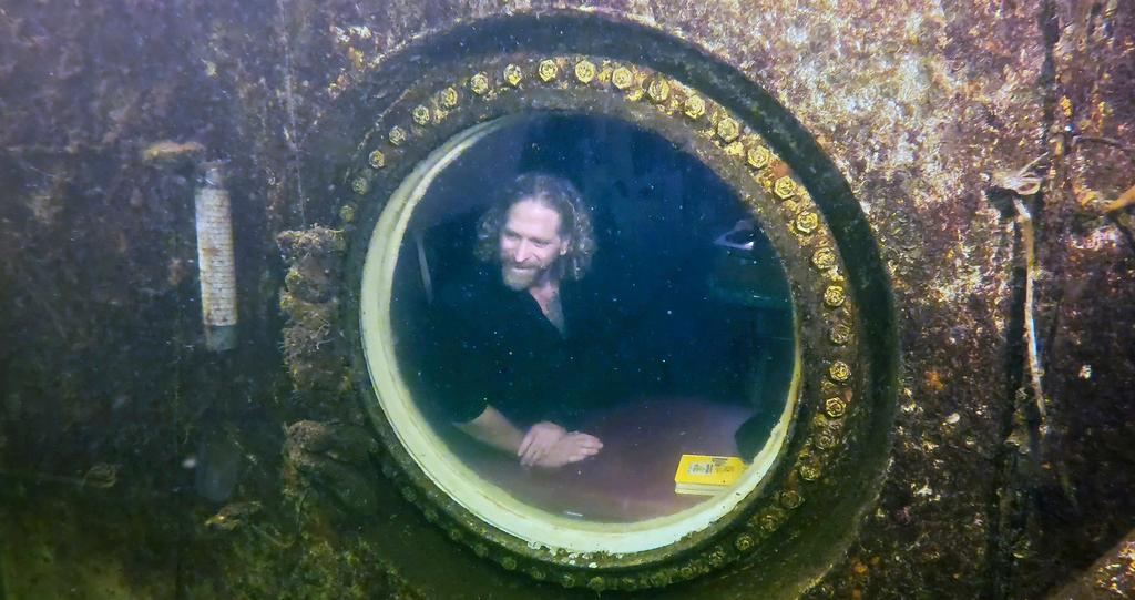 Dr. Joseph Dituri peers out of a large porthole at Jules' Undersea Lodge 