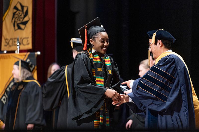 Purdue University President Mung Chiang presents a diploma to a graduate during commencement ceremonies. 