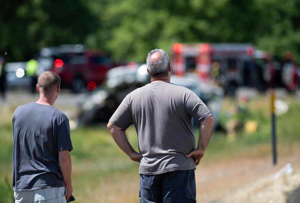 Joe Shipley, right, of Carlton, Ore., and another bystander watch emergency responders work at the scene of a multiple fatal crash, Thursday, May 18, 2023, along Interstate 5 in Albany, Ore.