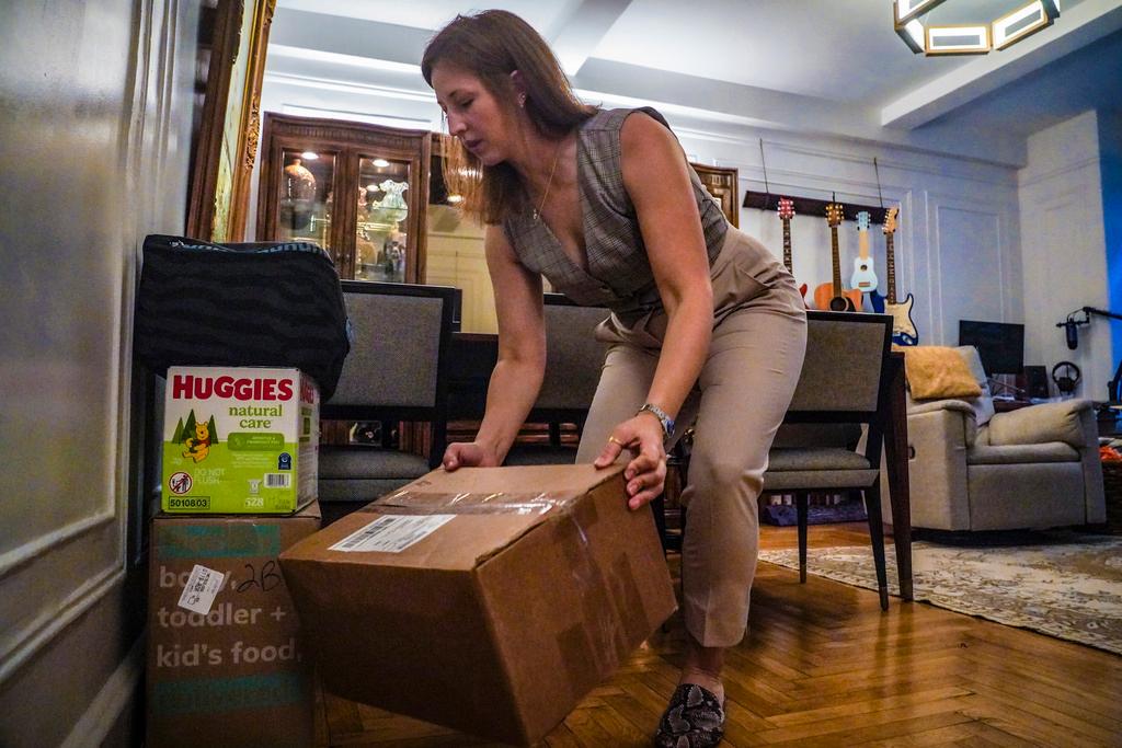 Jessica Ray moves deliveries from UPS, including baby food and diapers for her child, in her apartment 