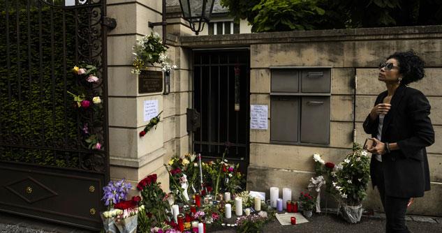 A woman looks at Tina Turner's gates with flowers left by mourners