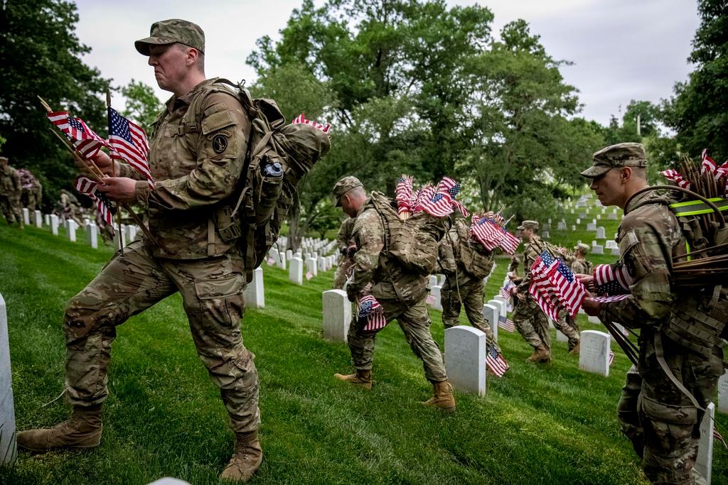 Members of the 3rd U.S. Infantry Regiment also known as The Old Guard place flags in front of each headstone for "Flags-In" at Arlington National Cemetery