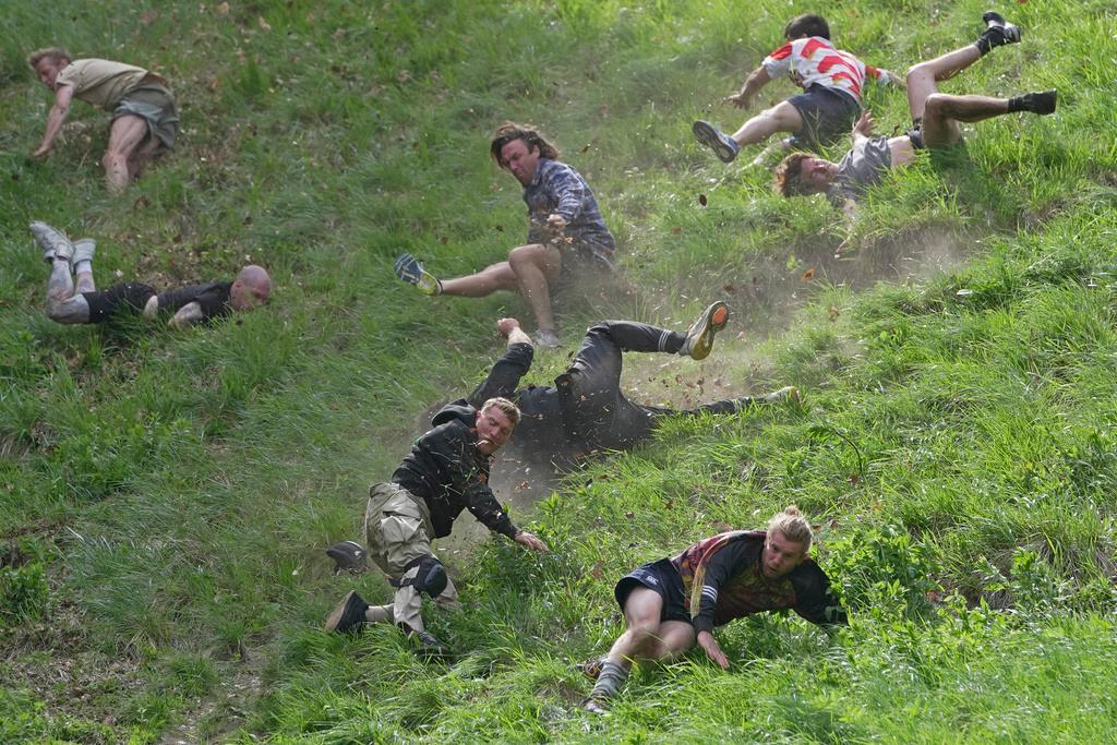 Participants compete in the men's downhill race during the Cheese Rolling contest at Cooper's Hill in England