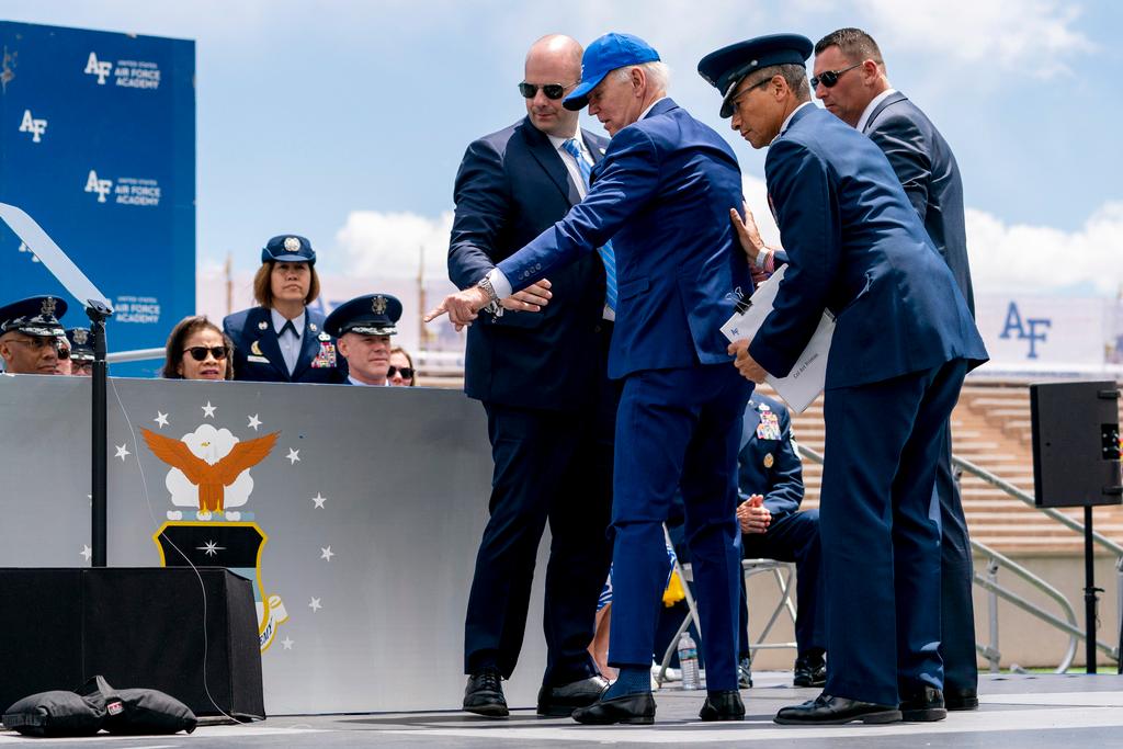 President Joe Biden points to sandbags after falling on stage during the 2023 United States Air Force Academy Graduation Ceremony at Falcon Stadium