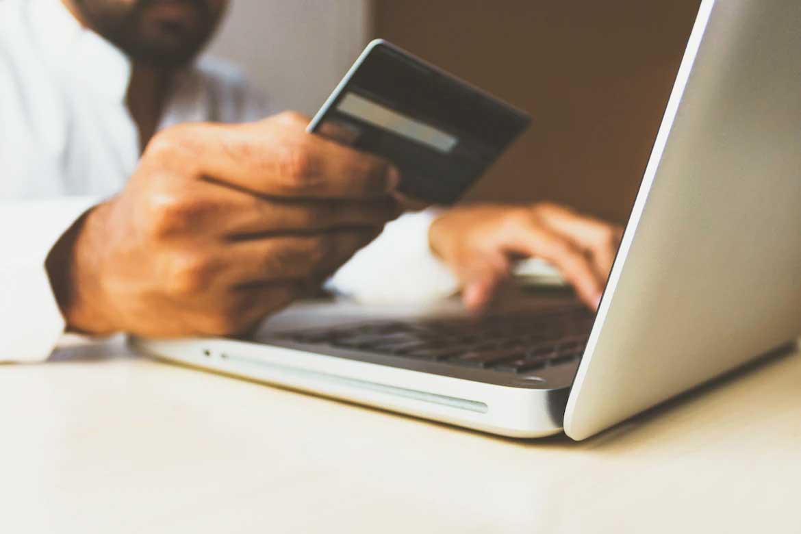 Man holding credit card in front of computer