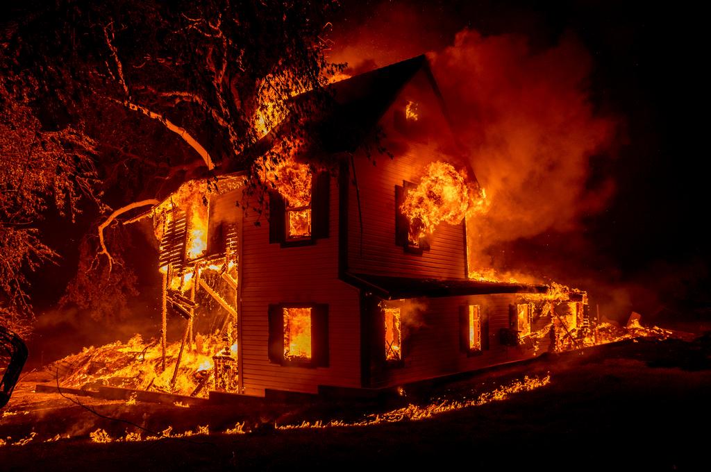 A home burns as the Dixie fire jumps Highway 395 south of Janesville, Calif.