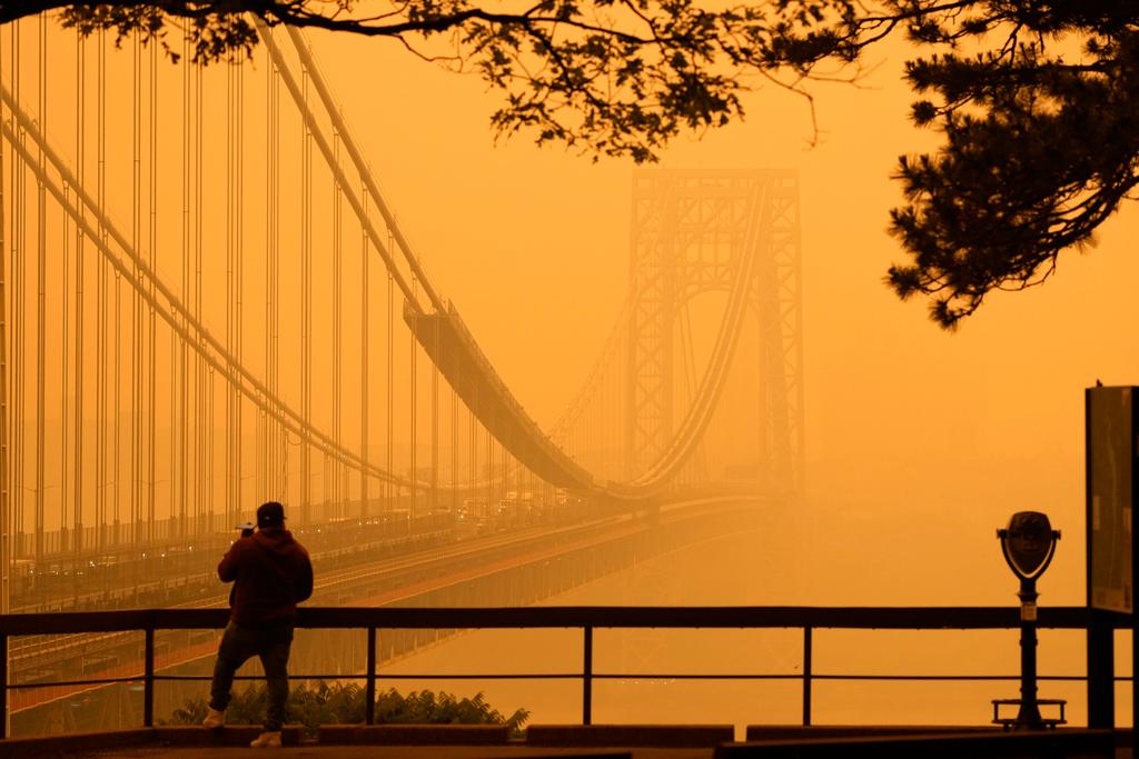 A Man talks on his phone as he looks through the haze at the George Washington Bridge from Fort Lee, N.J.
