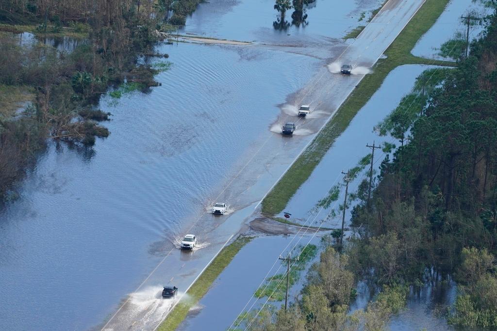Cars drive on a flooded street caused by Hurricane Ian 