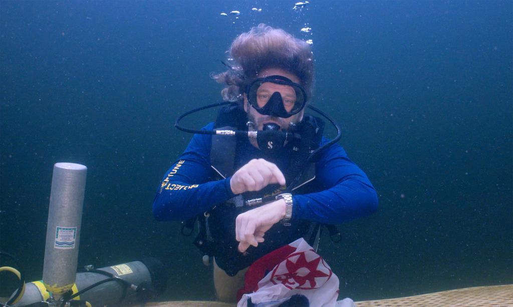 Explorer and medical researcher Dr. Joseph Dituri points to his watch while underwater 