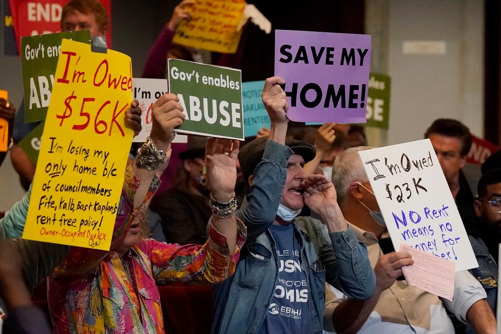 People who support ending the eviction moratorium yell and hold up signs during a Oakland City Council special community and economic development committee at City Hall in Oakland, Calif.