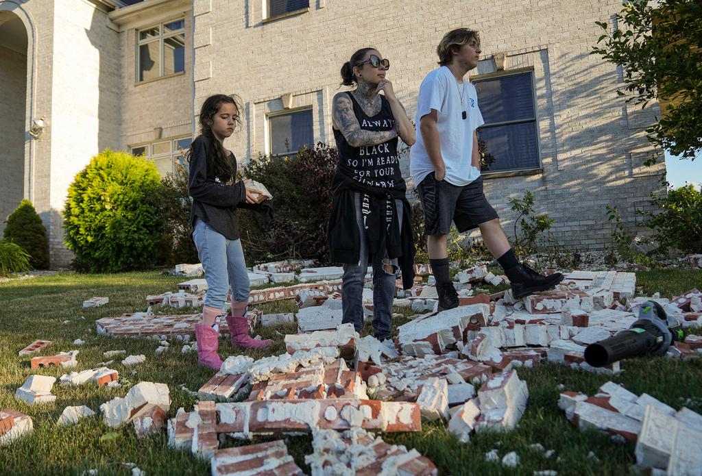 Nora Stoner, 9, her mom, Jackie Stoner, and brother, Christian Stoner, 15, survey tornado damage in front of their home