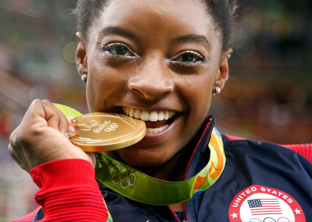 Simone Biles bites her gold medal