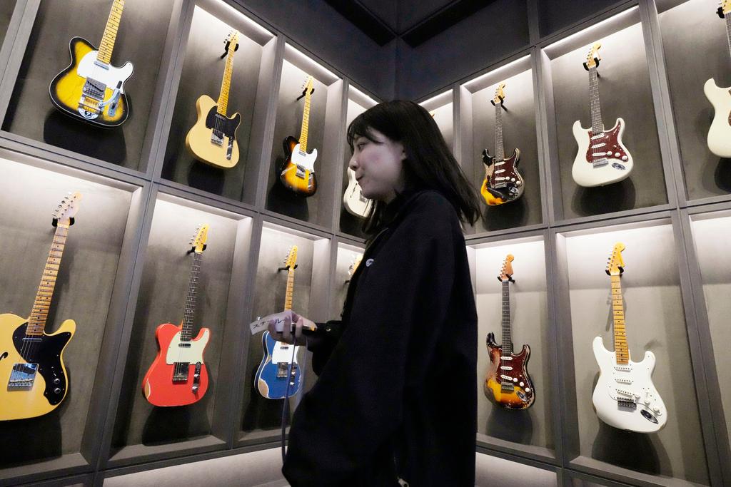 A staff member walks past Fender guitars on display at the opening ceremony of its Tokyo store Thursday, June 29, 2023