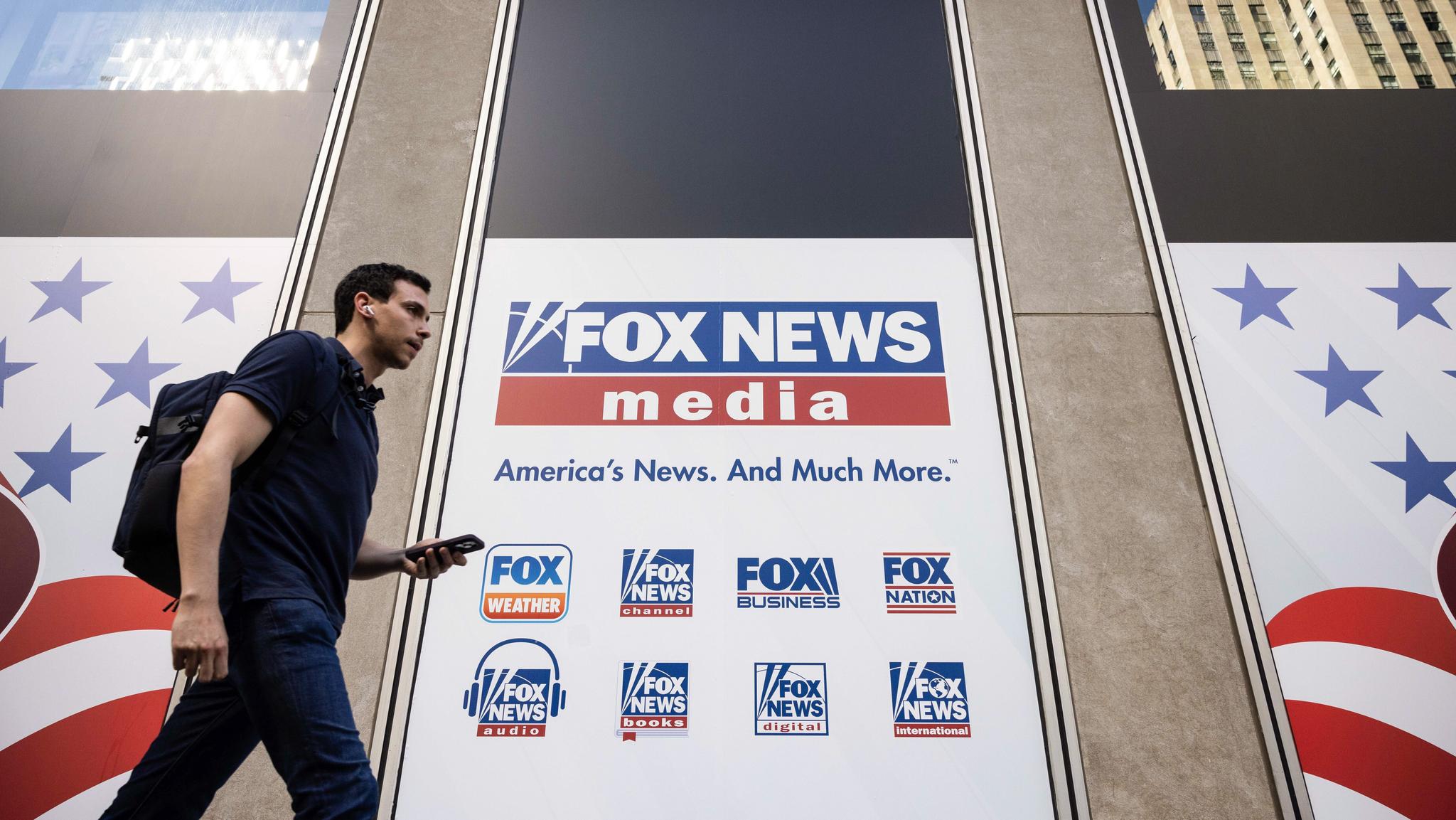 Man walking by a Fox News media sign