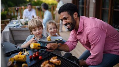 A man tends a grill at a backyard barbecue