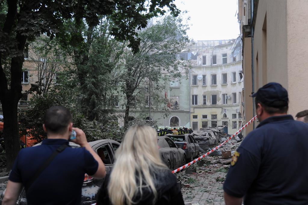 People watch as emergency service workers continue to search for victims after a Russian missile attack in Lviv, Ukraine
