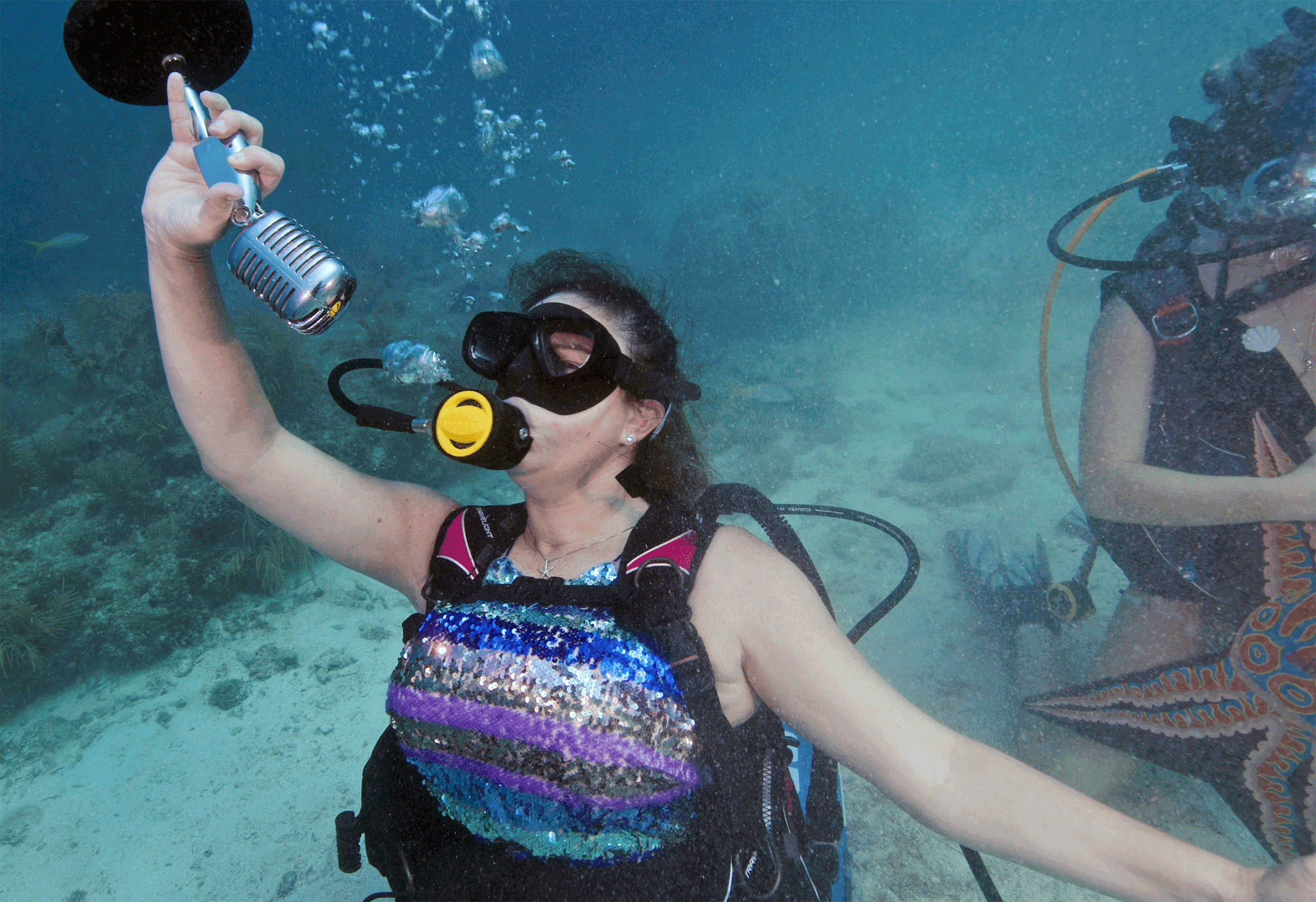 In this photo provided by the Florida Keys News Bureau, Kristen Livengood, left, pretends to sing underwater, Saturday, July 8, 2023