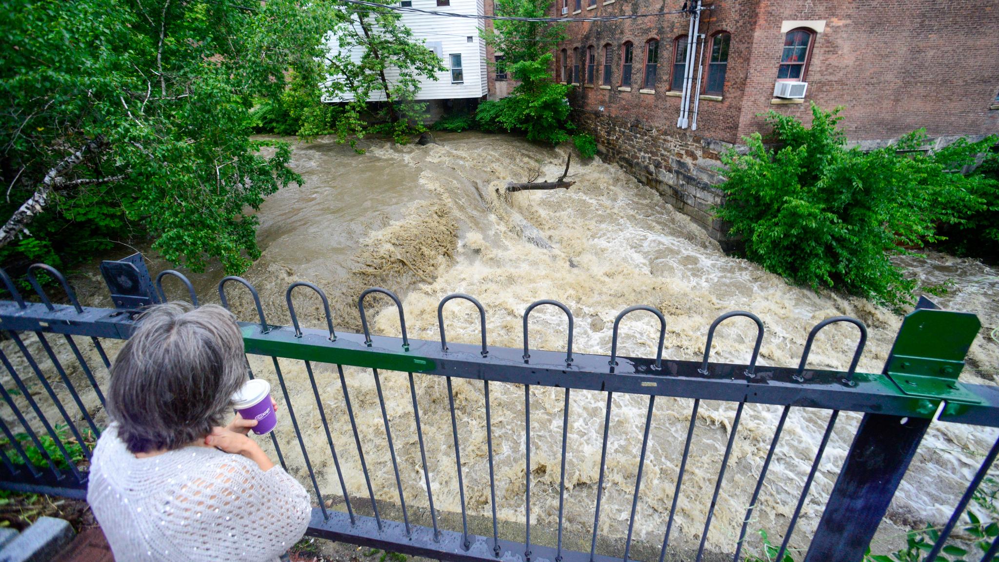 Woman standing on a deck watching a huge amount of water flow through a brook