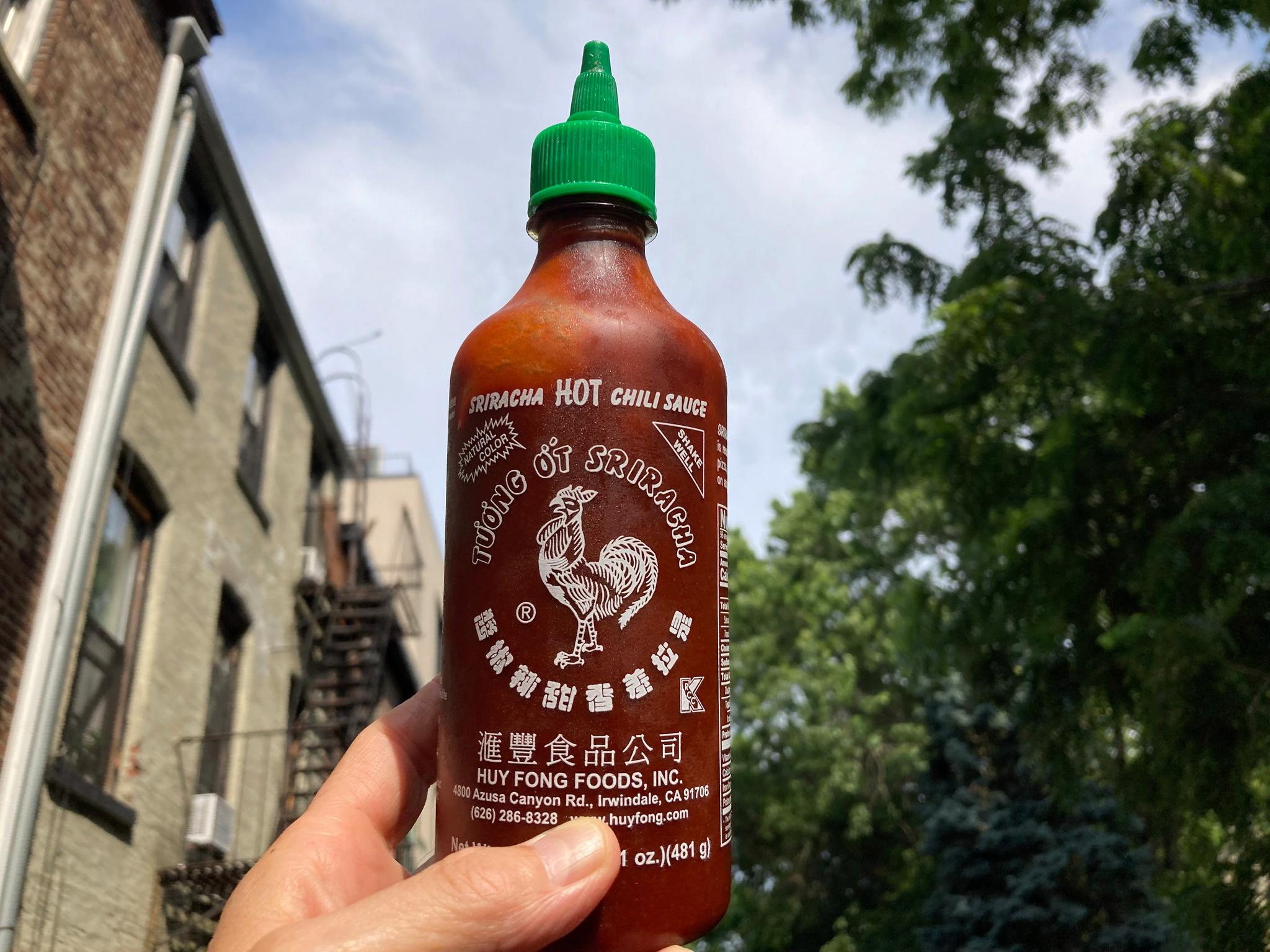 Man holding bottle of red hot sauce