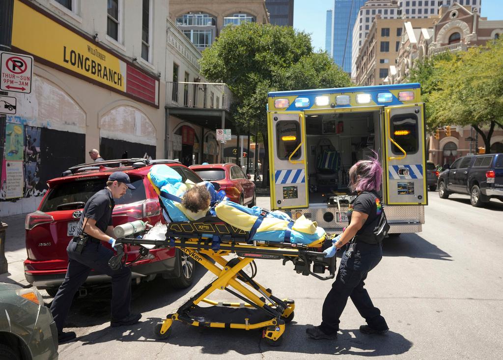 Austin-Travis County Emergency Medical Services medics B. Kurtze, left, and C. Cadena transport a man on East 6th Street in Austin, Texas, to the hospital for a heat-related issue