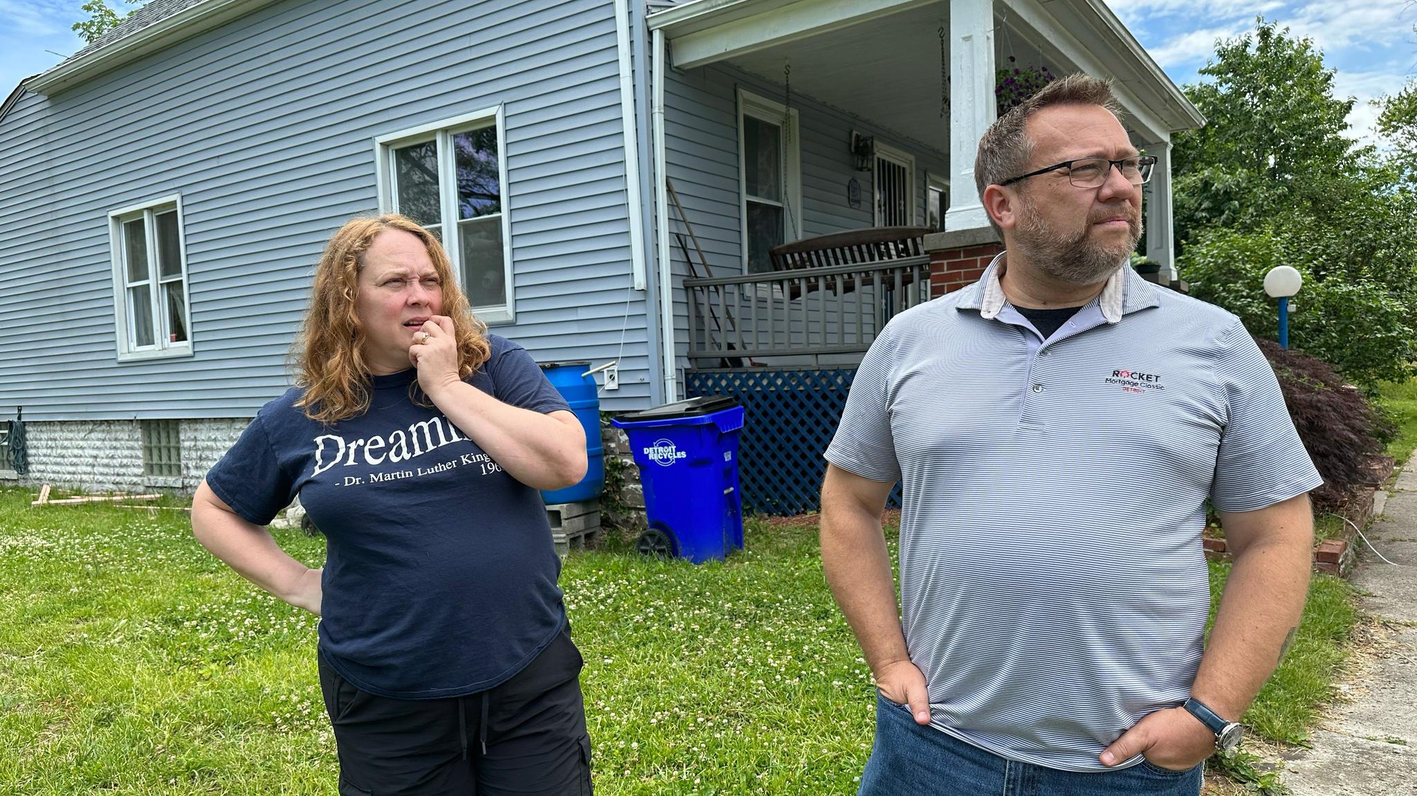 Wife and husband interviewed outside of their blue home