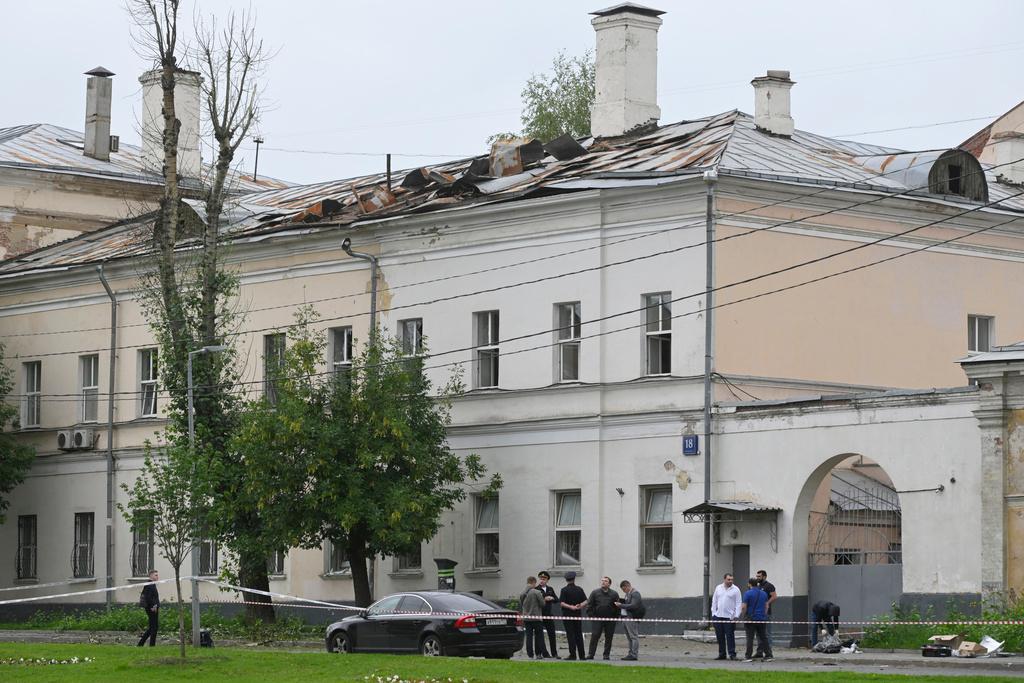 Investigators examine an area next to a damaged building after a reported drone attack in Moscow, Russia