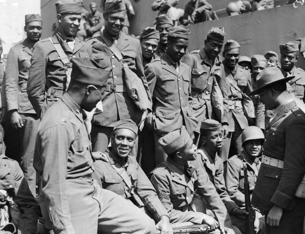 (1942) An African American Chaplin shown wearing a campaign hat talking to troops on their way to a fighting zone
