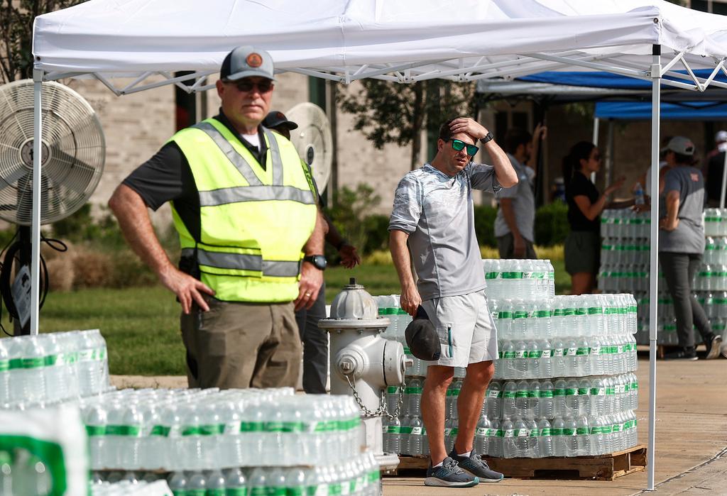 People stand by cases of bottled water as the City of Germantown gives them out to residents on Monday, July 24, 2023 at Forest Hill Elementary School in Germantown, Tenn.