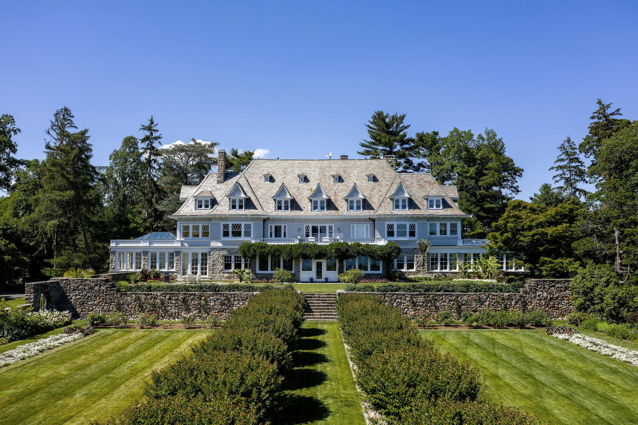 Large white house with about 25-30 windows and a manicured lawn