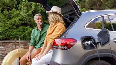 Man and woman sitting in trunk of charging EV car