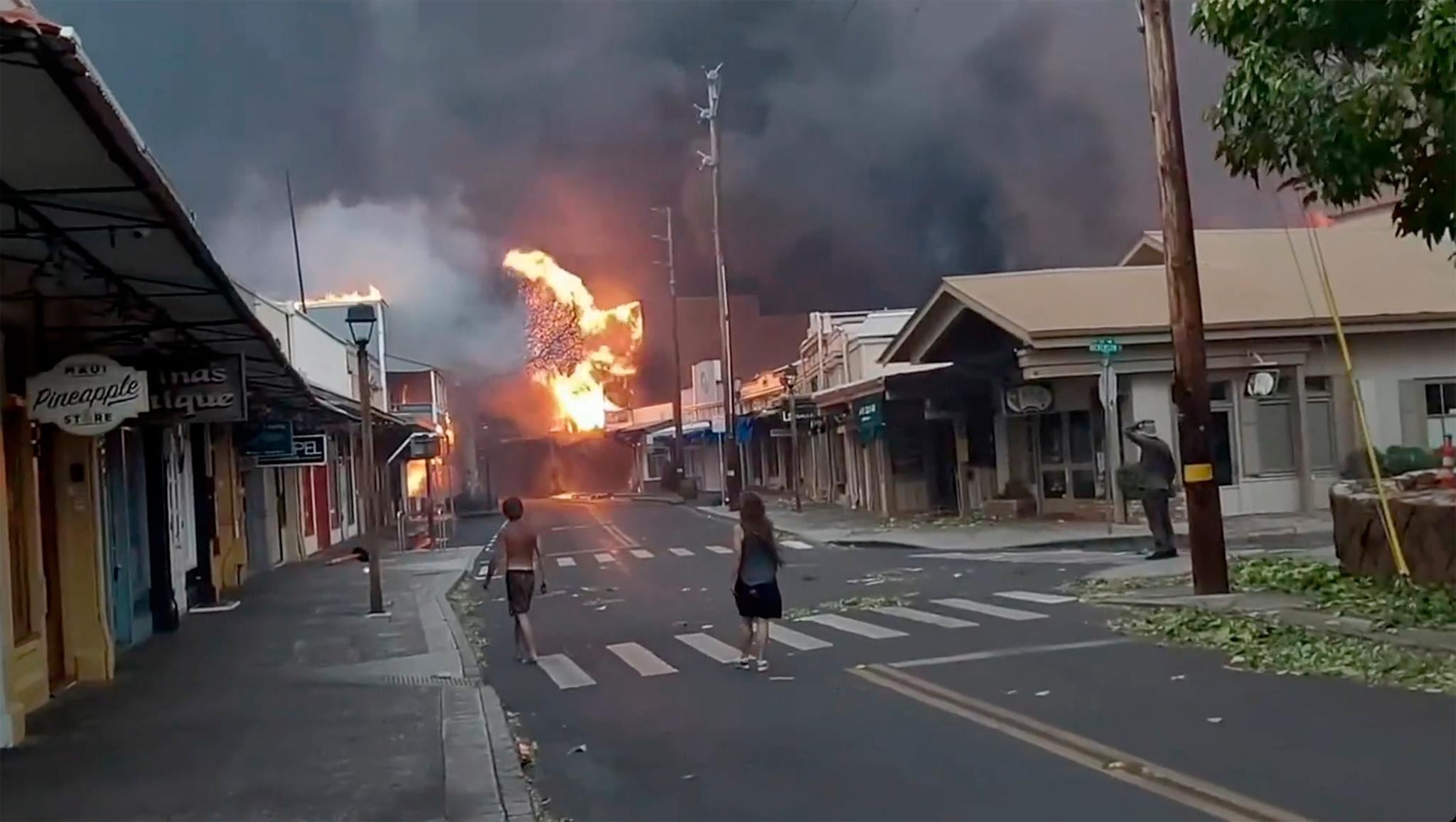 People watch as smoke and flames fill the air from raging wildfires on Front Street in downtown Lahaina, Maui