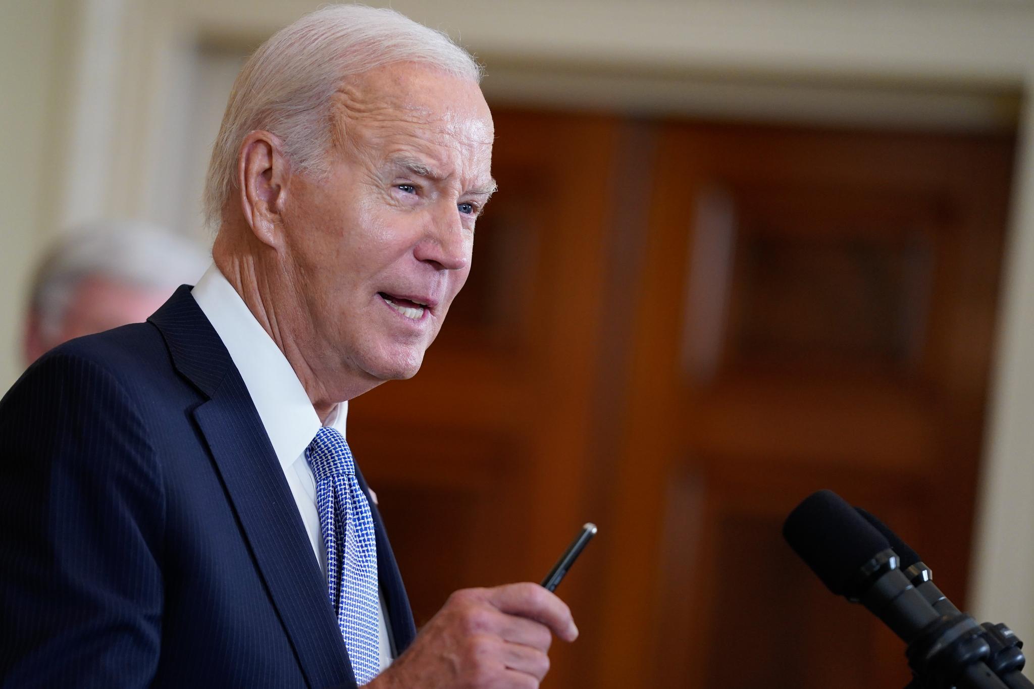 Pres. Biden speaking into a microphone, wearing a suit