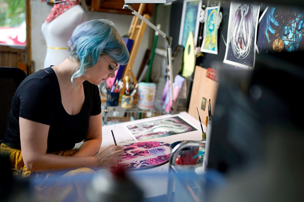 Artist Kelly McKernan paints in their studio Tuesday, Aug. 15, 2023, in Nashville, Tenn.