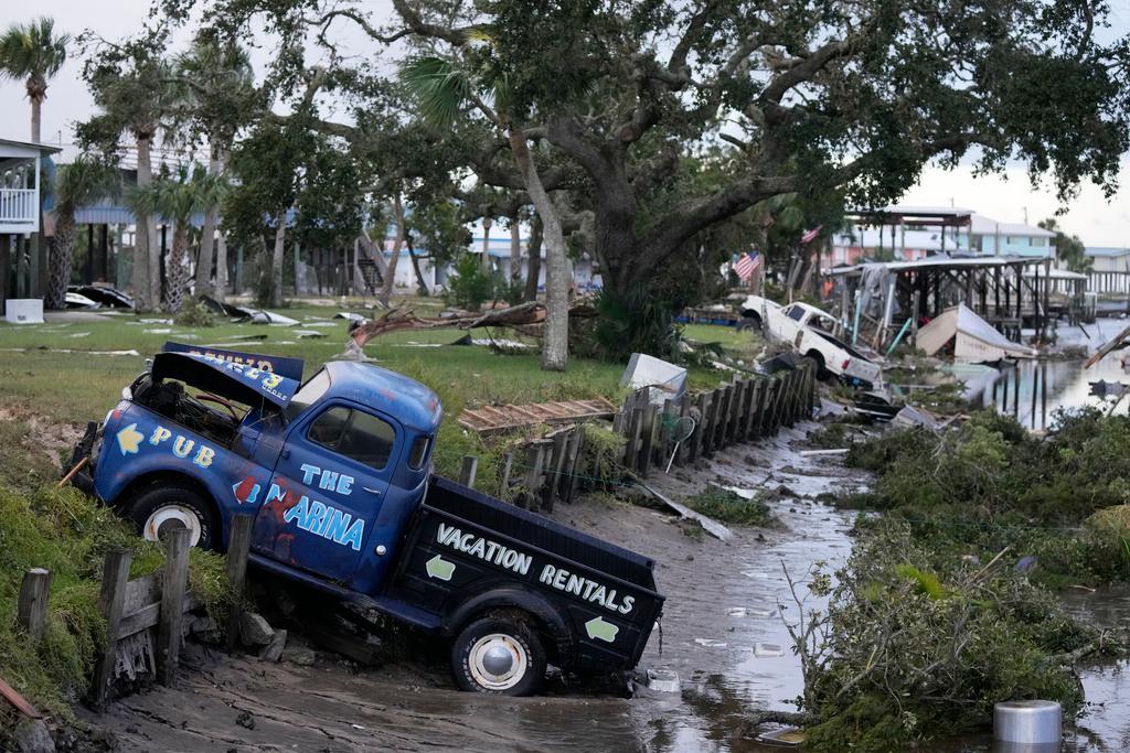 Pick up trucks and debris lie strewn in a canal in Horseshoe Beach, Fla.