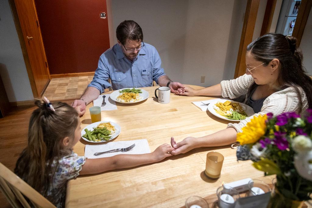 Shane Alderson, his wife, Alisha, and their daughter, Adeline, 5, pray before dinner at their home in Baker City, Ore. Because of the closing of Baker City's only obstetrical unit, the family is traveling to the Boise, Idaho area, a little over 100 miles away, to give birth.