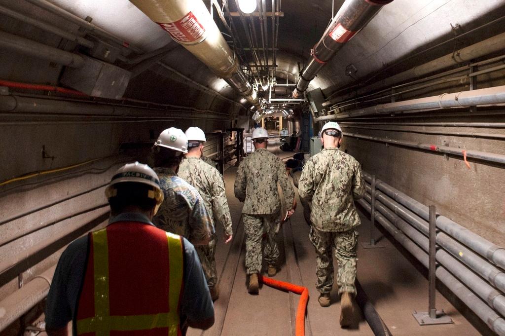In this photo provided by the U.S. Navy, Rear Adm. John Korka, Commander, Naval Facilities Engineering Systems Command (NAVFAC), and Chief of Civil Engineers, leads Navy and civilian water quality recovery experts through the tunnels of the Red Hill Bulk Fuel Storage Facility, near Pearl Harbor, Hawaii, Dec. 23, 2021.