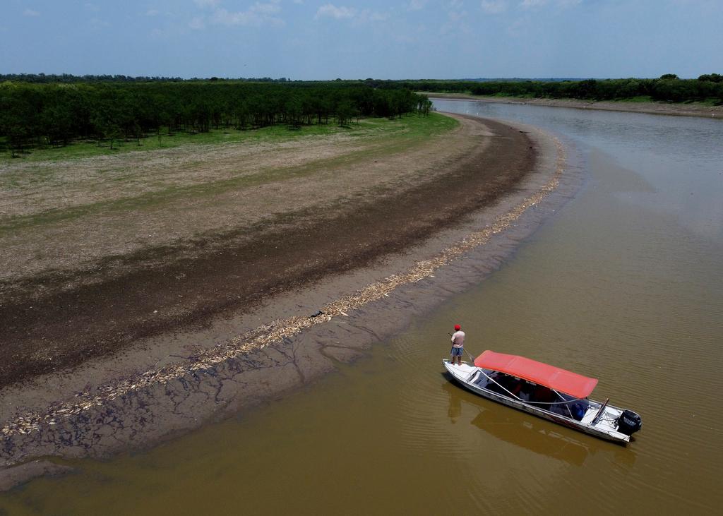 A fisherman stands on his boat as he navigates near thousands of dead fish awash on the banks of Piranha Lake due to a severe drought in the state of Amazonas, in Manacapuru, Brazil, Wednesday, Sept. 27, 2023.